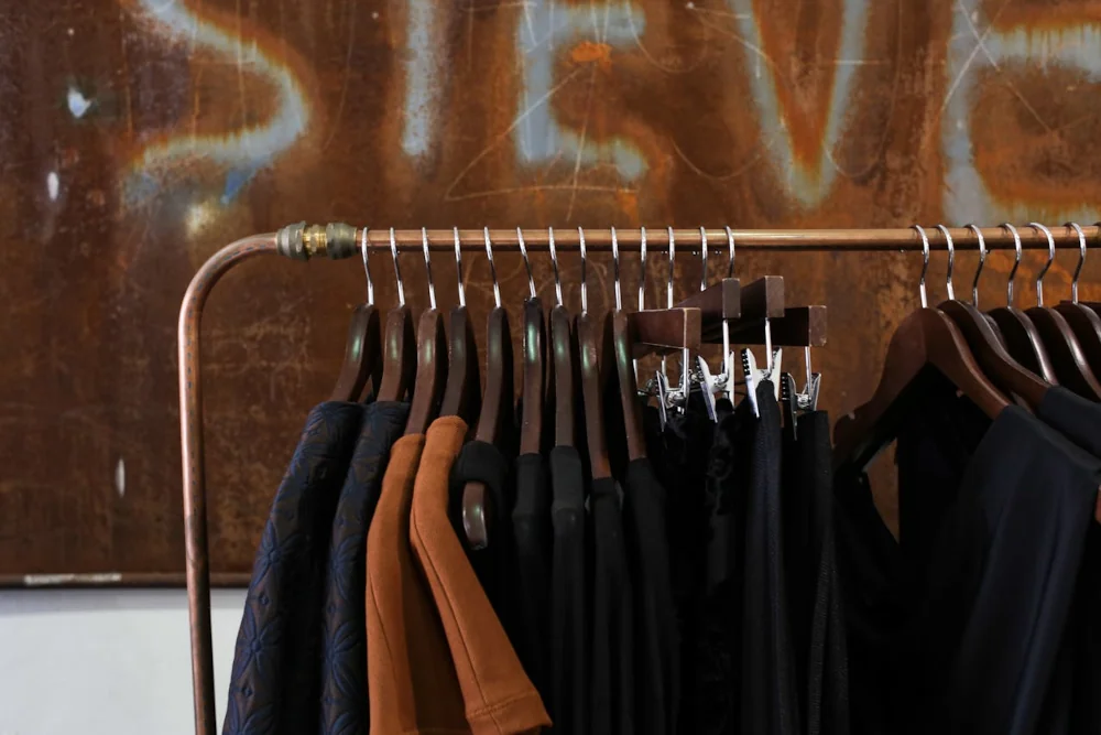 A collection of dark, pre-loved garments on a rack, ideal for practicing sewing fundamentals